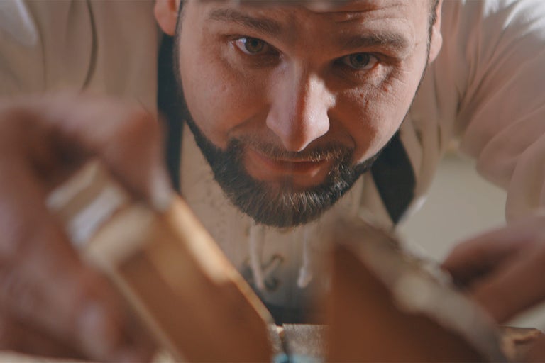 Detailní záběr řemeslníka pracujícího se dřevem pomocí dláta