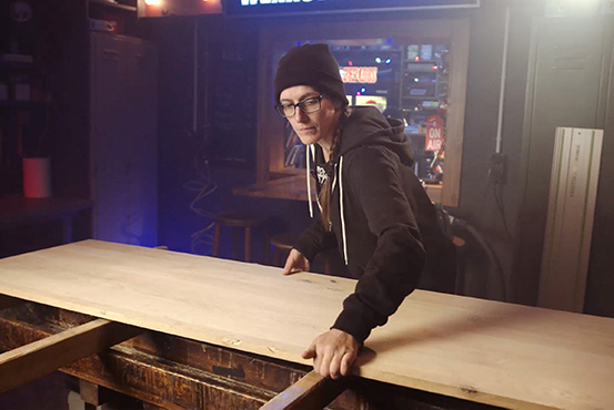 Žena pracuje s dřevěnou deskou na pracovním stole.