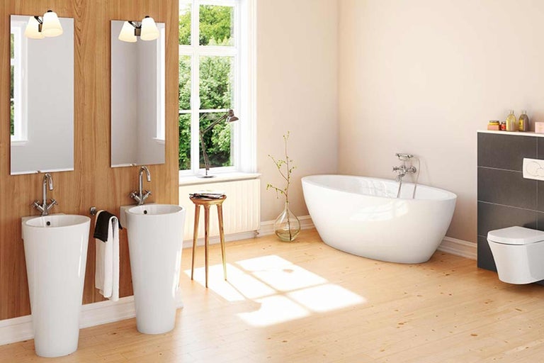 Světlá koupelna s volně stojící vanou, umyvadlovými sloupy a dřevěnou podlahou