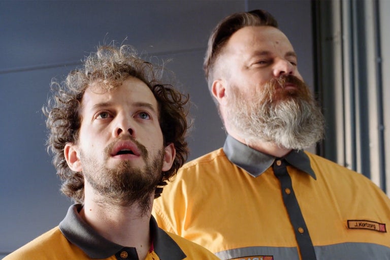 Dva řemeslníci v pracovních oděvech se dívají nahoru