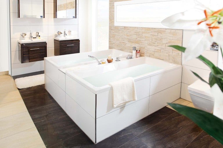 Moderní koupelna s dvojitou vanou, umyvadly se skříňkami a světlými obklady