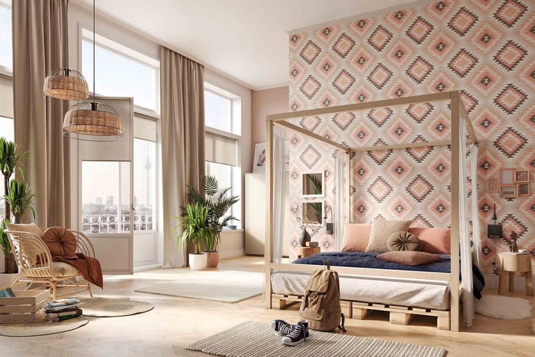 Světlá ložnice s postelí s nebesy z paletového dřeva, geometrickou tapetou, ratanovým křeslem, pletenými lampami a velkými okny.