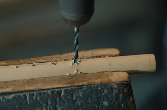 Vrtačka vrtá otvor do kusu dřeva upnutého ve svěráku.
