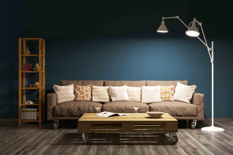 Obývací pokoj s pohovkou, konferenčním stolkem z palet, regálem a stojací lampou.