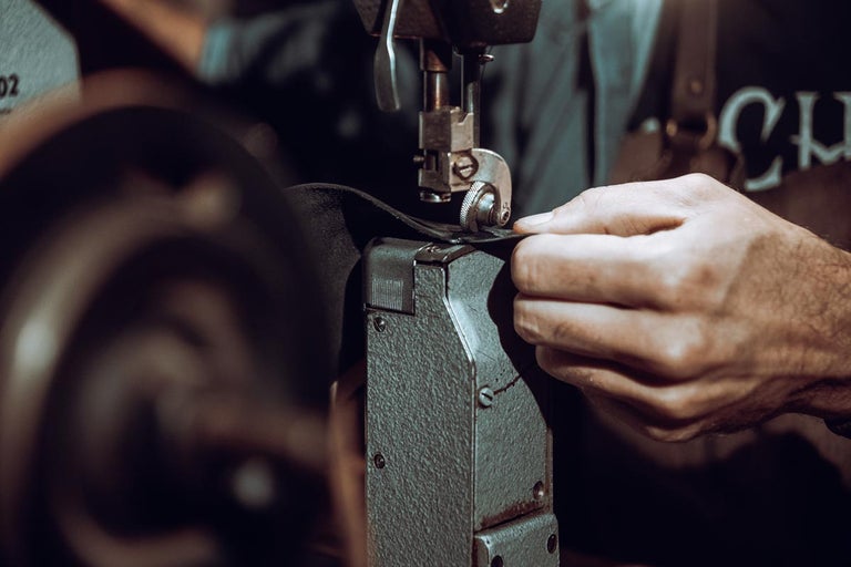 Detailní záběr osoby zpracovávající kůži šicím strojem