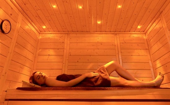 Žena relaxuje v dřevěné sauně s hodinami