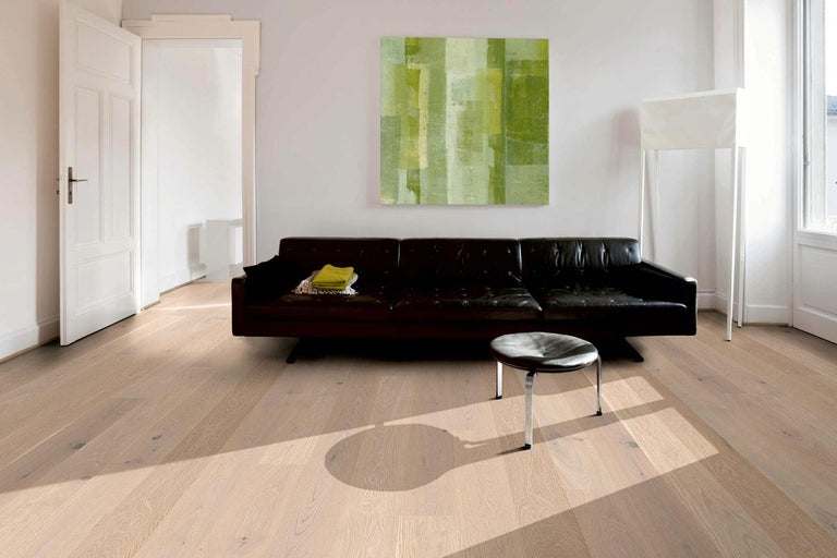 Světlá dřevěná podlaha v obývacím pokoji s pohovkou a uměleckým dílem