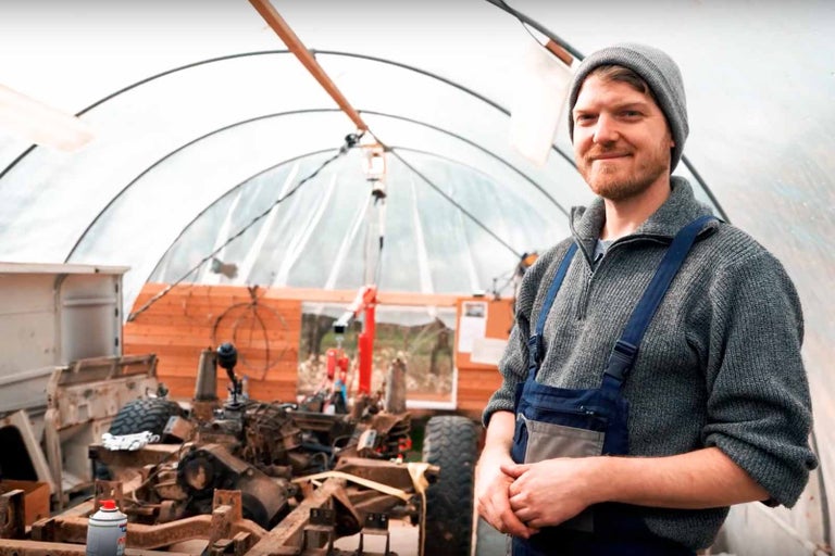 Muž v dílně s rámem vozidla v pozadí