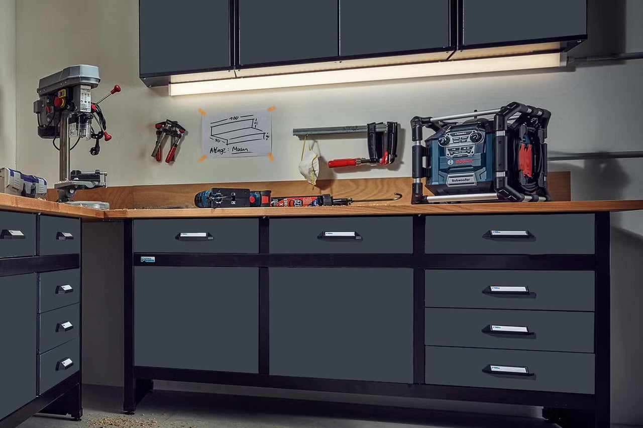 Pracovní stůl se zásuvkami, vrtačka a staveništní rádio v dílně