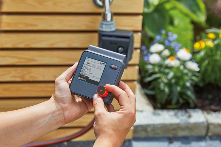 Osoba obsluhuje zavlažovací systém Gardena na vodovodním kohoutku v zahradě.