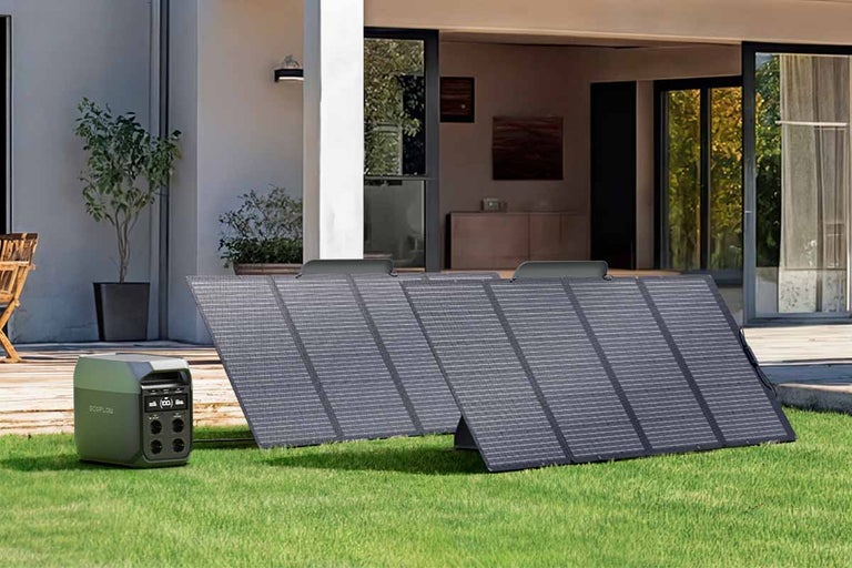 Přenosná napájecí stanice EcoFlow se dvěma skládacími solárními panely na trávníku před moderním domem.