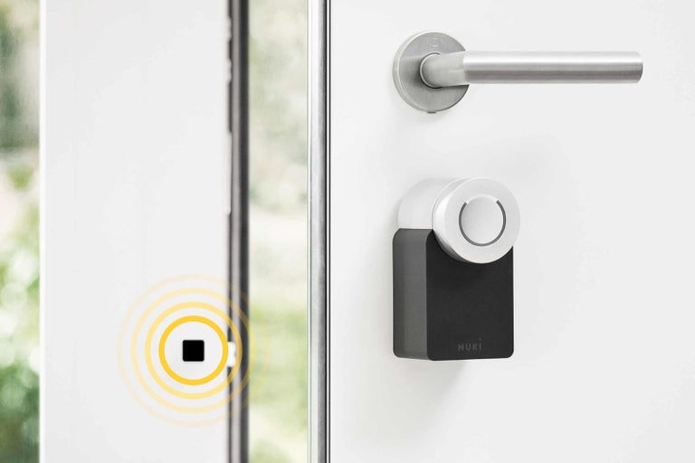 Detail dveří s chytrým zámkem Nuki a dveřním senzorem.