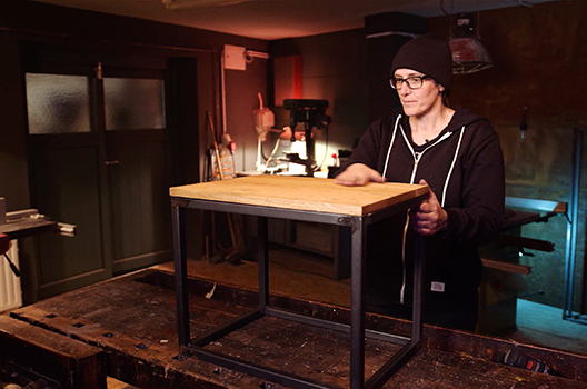 Žena v dílně s dřevěným stolem a kovovým rámem