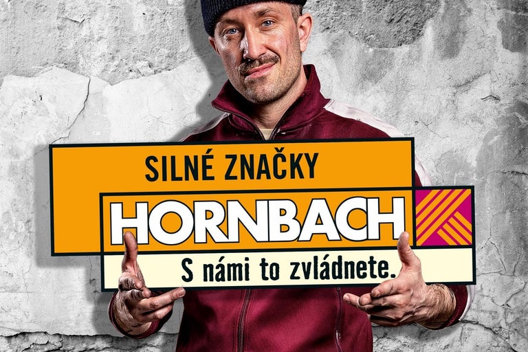 Muž prezentuje reklamní banner Hornbach se sloganem Silné značky. S námi to zvládnete.