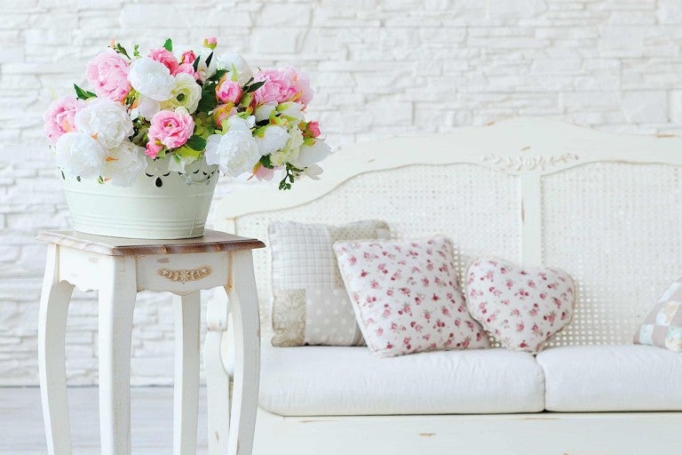 Dekorativní aranžmá s kyticí květin na odkládacím stolku a pohovce ve venkovském stylu