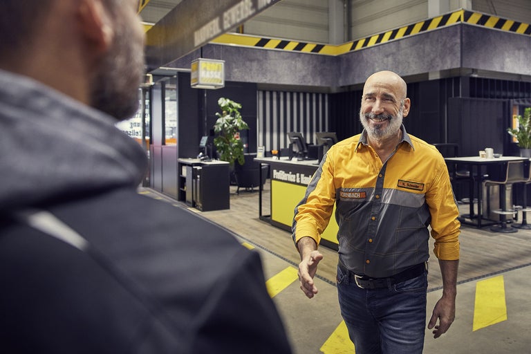 Zaměstnanec společnosti Hornbach vítá zákazníka v obchodě.