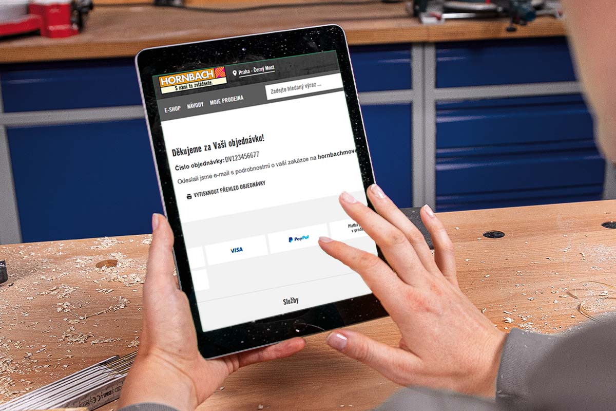 Osoba ovládá tablet se zobrazenou webovou stránkou Hornbach po dokončení objednávky v prostředí dílny.