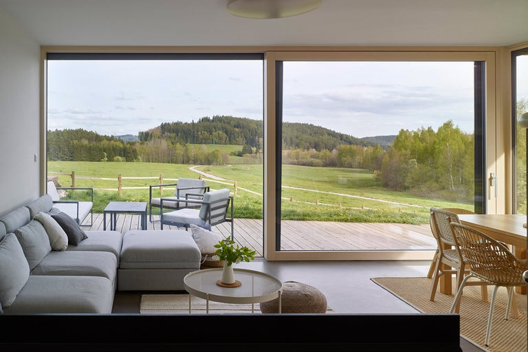 Světlý obývací pokoj s velkými okny a výhledem do přírody