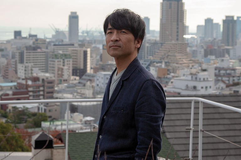 Muž v bundě před městskou scenérií