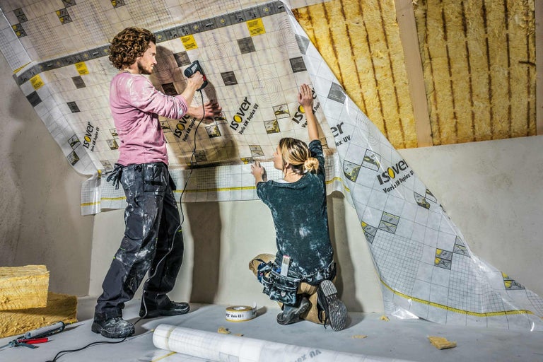 Dvě osoby připevňují parobrzdu Isover Vario KM Duplex UV na šikmou střechu.