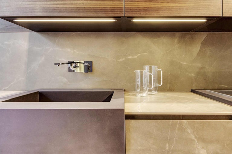 Detail moderní kuchyně s umyvadlem, baterií a dvěma skleněnými džbány