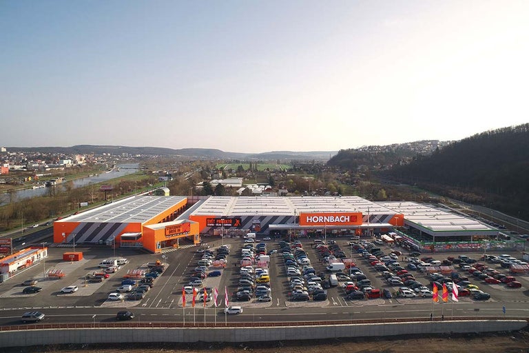 Letecký pohled na hobbymarket Hornbach s parkovištěm a okolní krajinou.