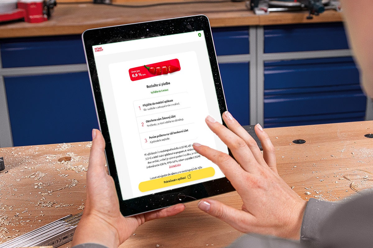 Osoba používá tablet v dílně k žádosti o splátkový prodej prostřednictvím Home Credit.