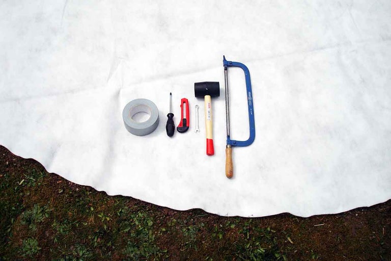 Nástroje jako lepicí páska, šroubovák, ulamovací nůž, klíč, gumové kladivo a rámová pila na zahradní textilii