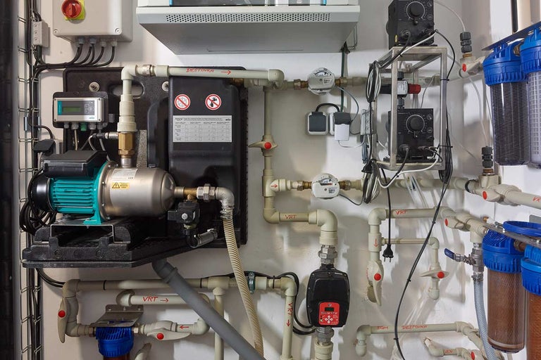 Instalace s vodním čerpadlem, měřicími přístroji a trubkami na zdi