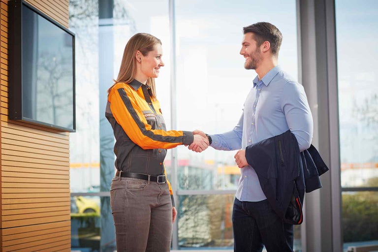 Dva lidé si potřásají rukou ve světlé místnosti.