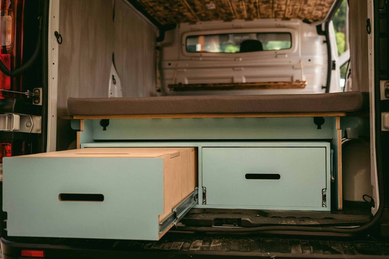 Interiér dodávky s postelí a zásuvkami