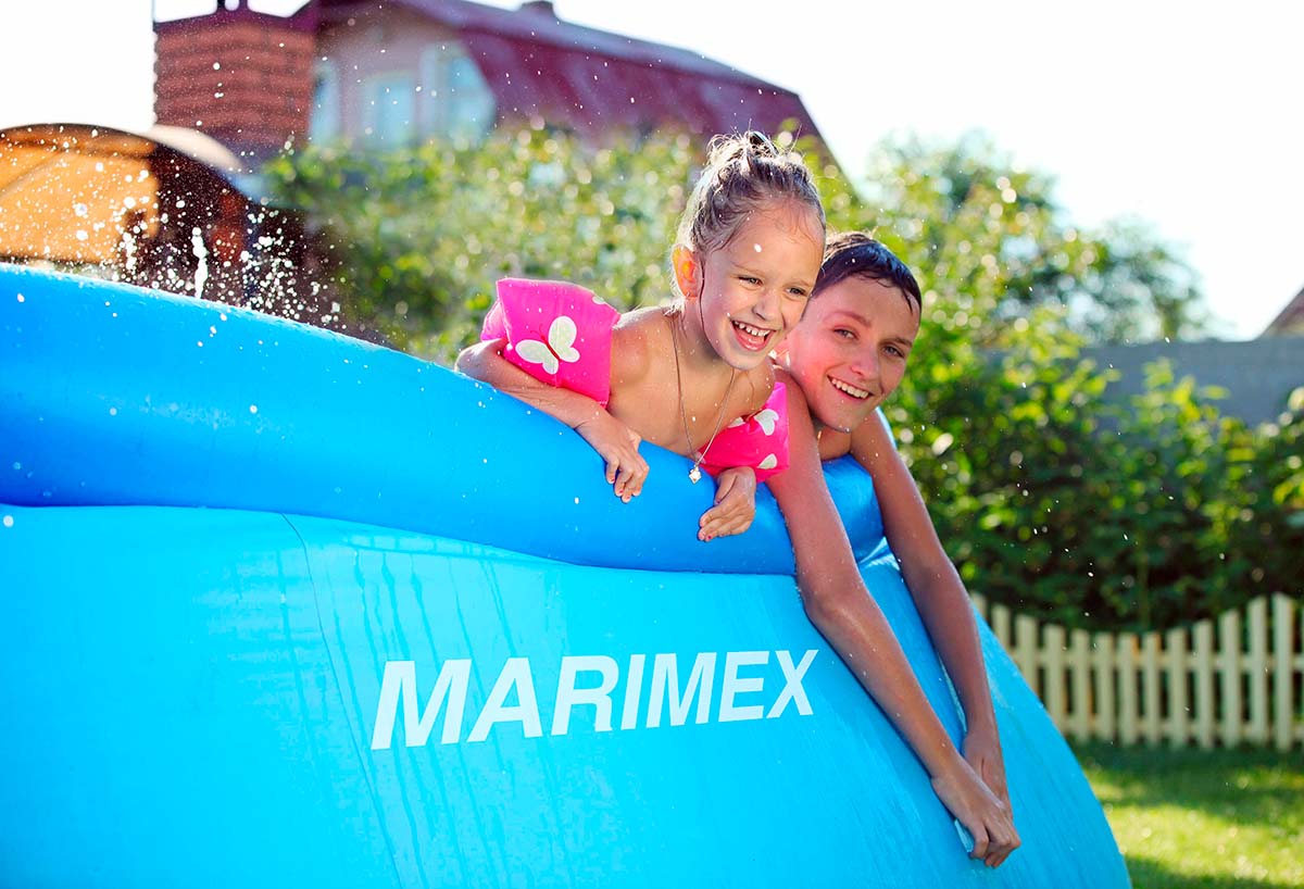 Dvě děti se baví v nafukovacím bazénu Marimex na zahradě.