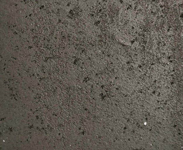 Detailní záběr na nerovný, hrubý povrch se zrnitou strukturou