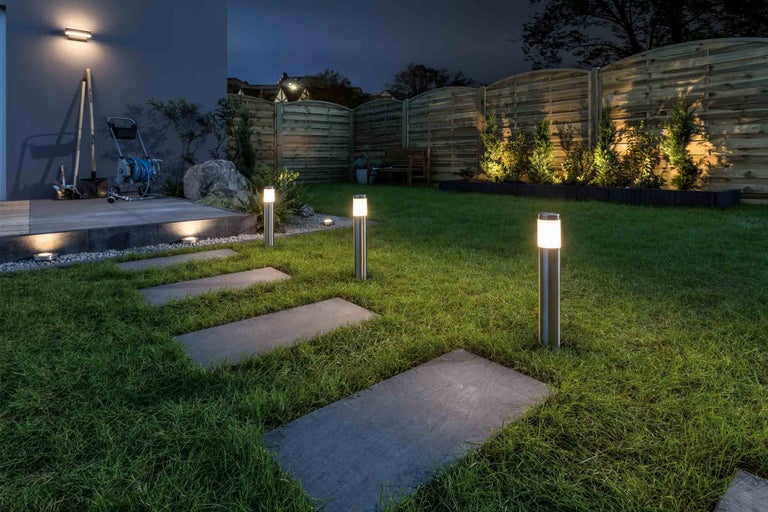 Osvětlená zahrada s trávníkem, kamennou cestou a sloupkovými svítidly