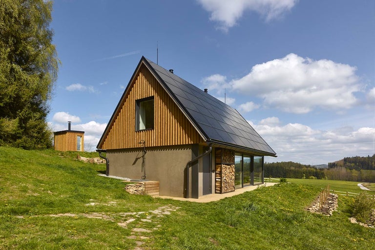 Moderní dům s dřevěným obkladem, solárním systémem a velkými okny ve venkovském prostředí