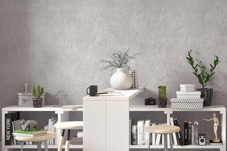 Dekorativní police s knihami, rostlinami a bytovými doplňky před šedou stěnou