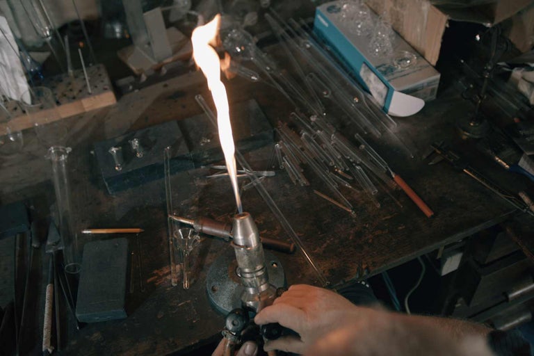 Scéna sklářské dílny s nástroji a skleněnými tyčemi na stole