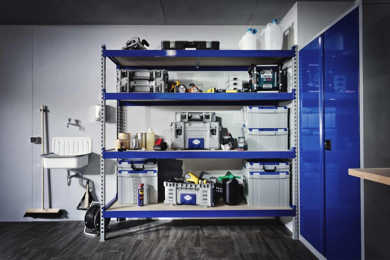 Regálový systém s nářadím a příslušenstvím v dílně nebo garáži. Regálový systém je vybaven různými kufříky s nářadím, nářadím a kontejnery.