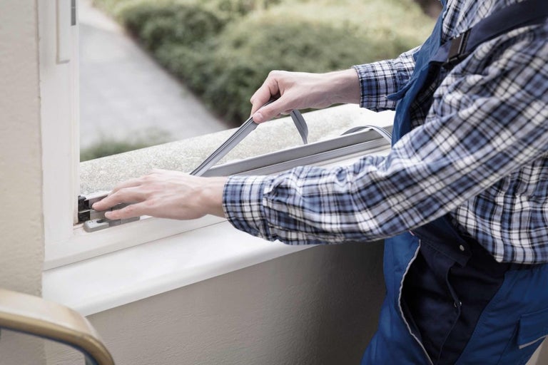 Muž připevňuje těsnění k oknu.