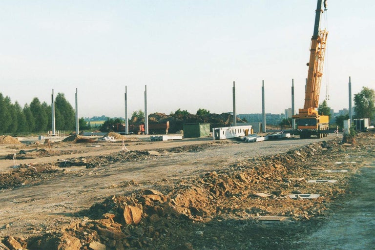 Staveniště s jeřábem, betonovými pilíři a stavebními materiály