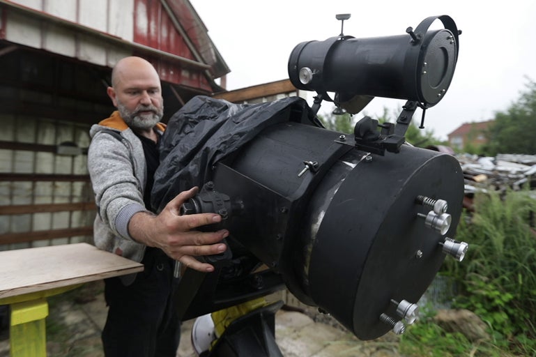 Muž manipuluje s velkým astronomickým teleskopem venku