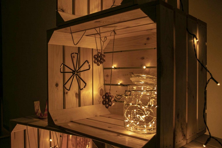 Dřevěná bedna zdobená světelným řetězem, skleněnou nádobou a přívěsky