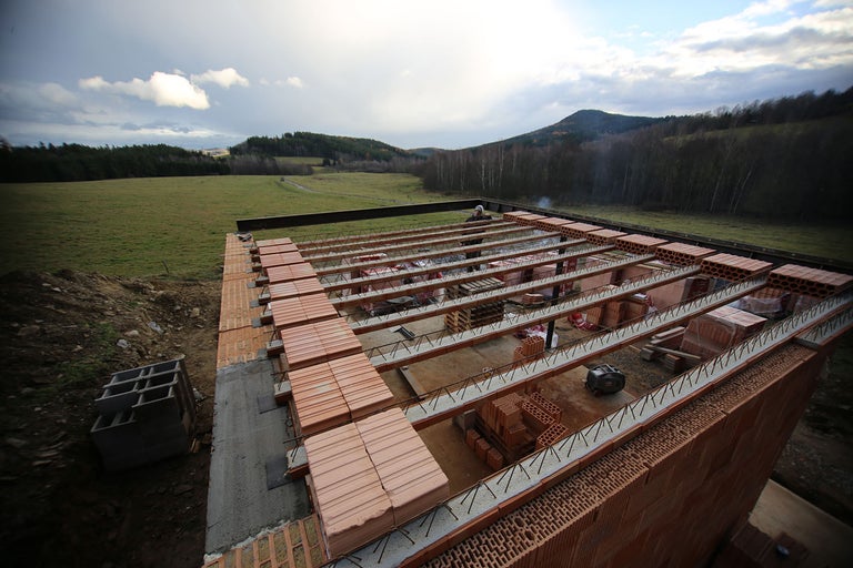 Staveniště s cihlami a ocelovými nosníky pro stavbu domu