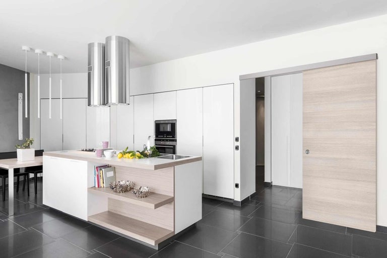 Světlá kuchyně s kuchyňským ostrůvkem, odsavačem par a posuvnými dveřmi