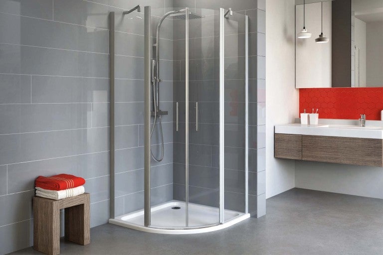 Rohová sprcha se sprchovou vaničkou v koupelně s umyvadlovou skříňkou a ručníky