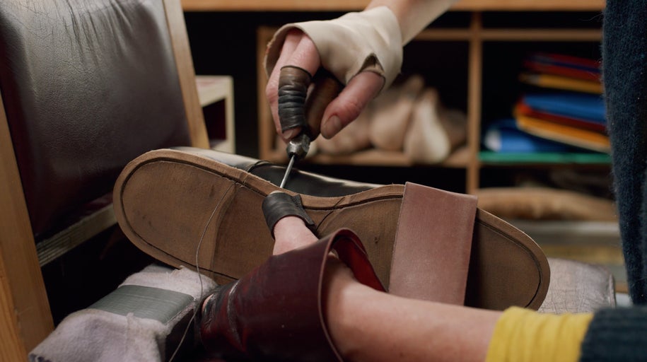 Švec šije koženou botu šídlem