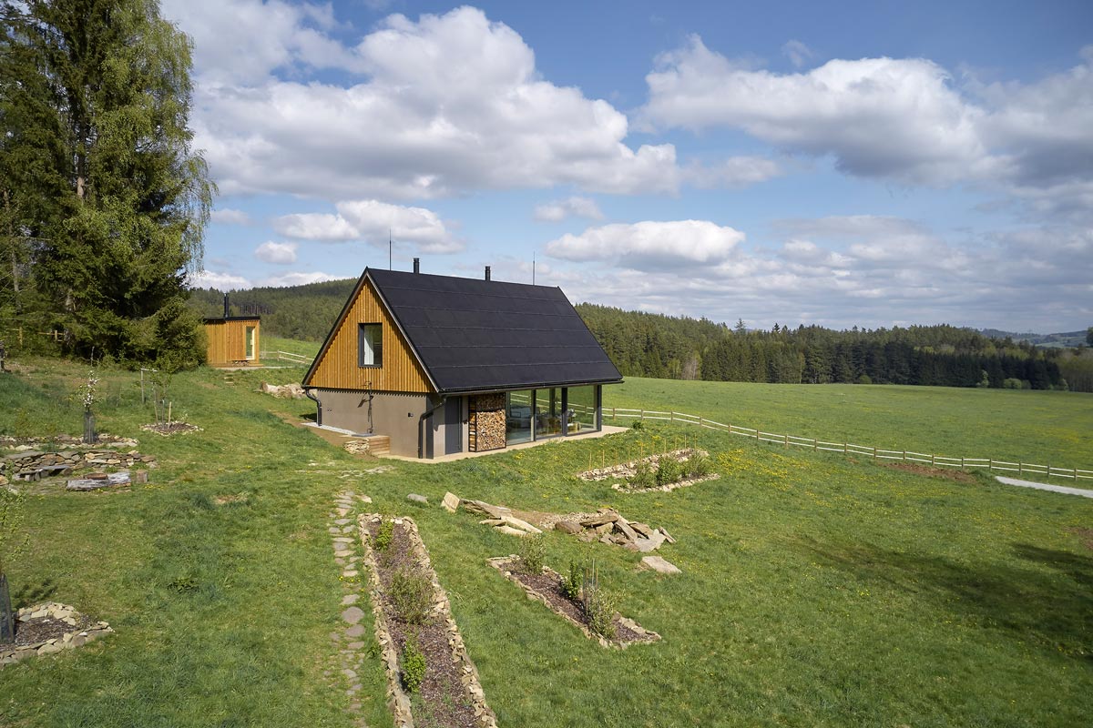 Vnější pohled na moderní dům se solární střechou ve venkovském prostředí.