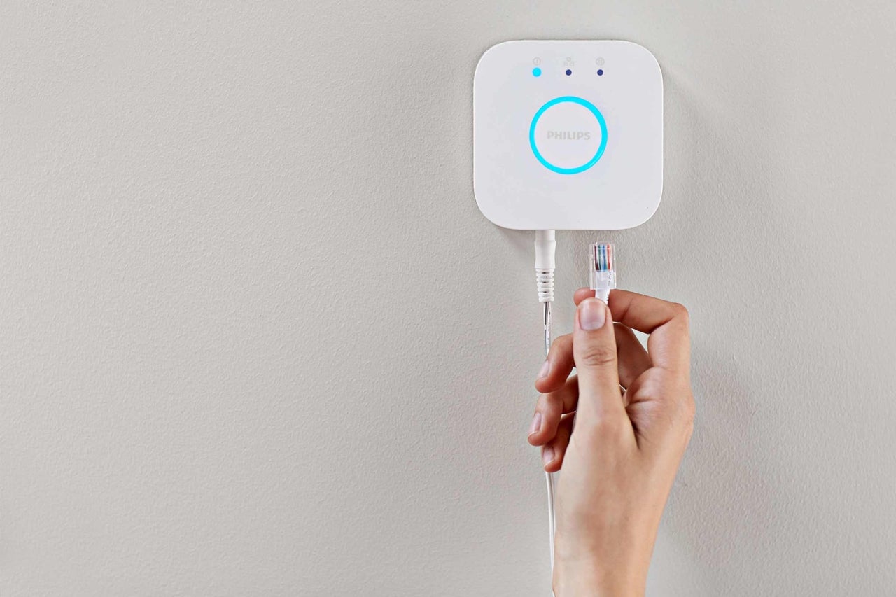 Philips Hue Bridge se síťovým kabelem v ruce