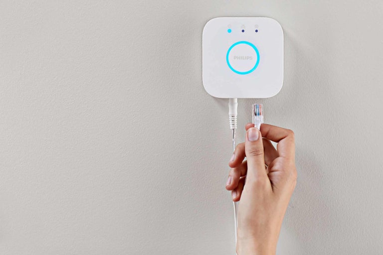 Philips Hue Bridge se síťovým kabelem v ruce