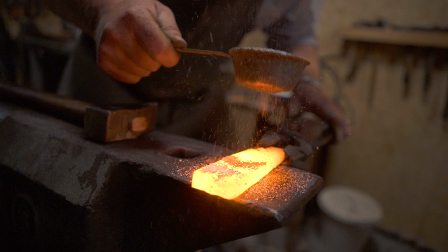 Kovář zpracovává žhavý kov na kovadlině